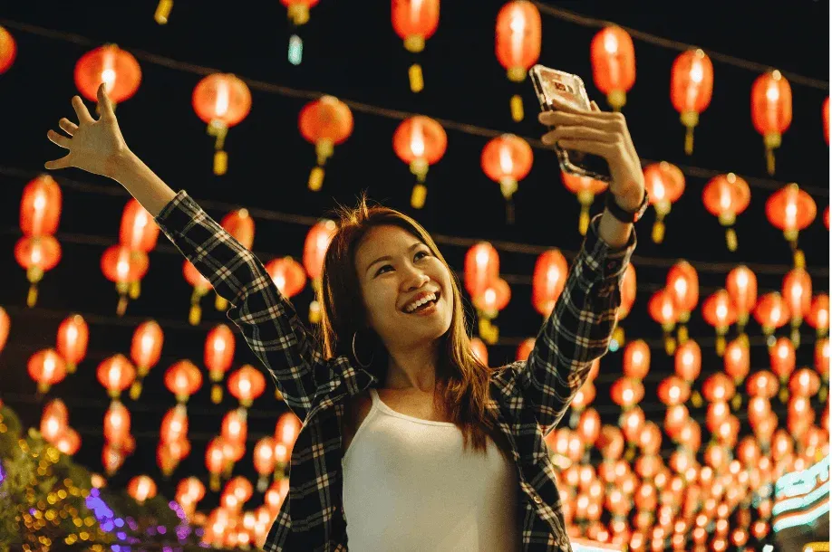A woman taking a selfie video under lanterns at night
