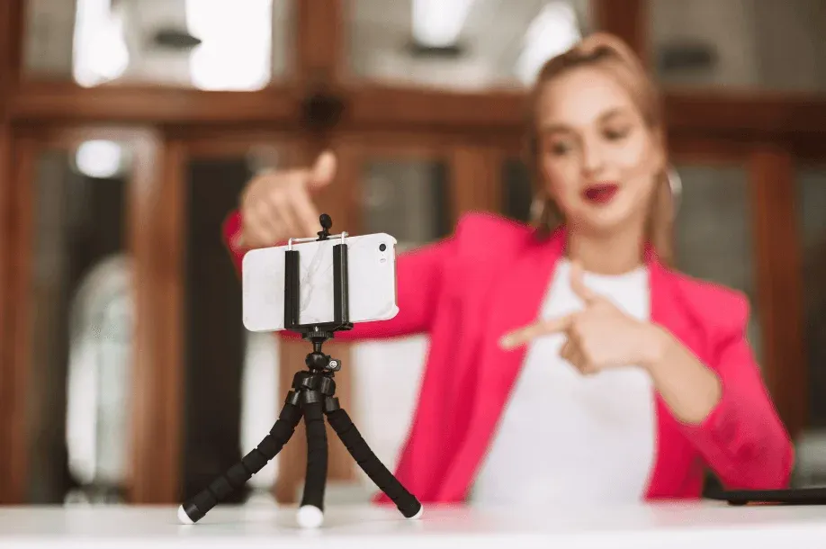 A woman recording herself with a smartphone on a small tripod