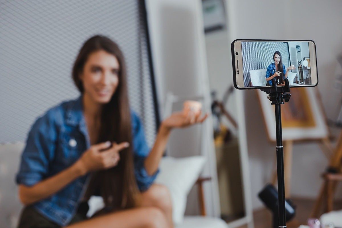 A woman sitting in front of a smartphone on a tripod