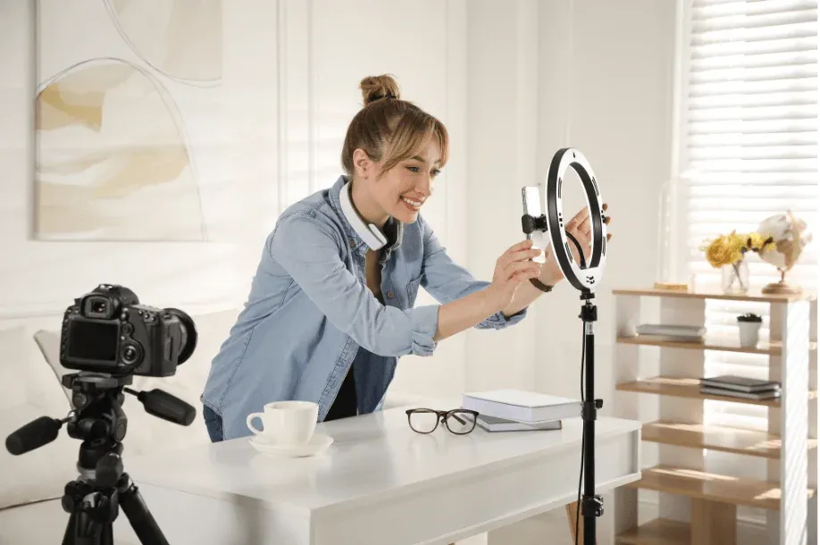 A woman setting up a camera and ring light indoors