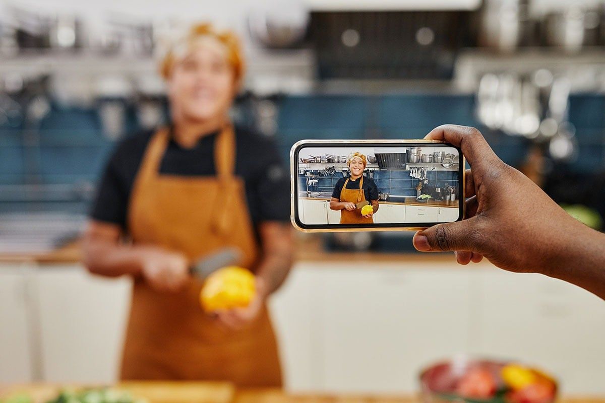 A smartphone filming a cook in a well-lit kitchen